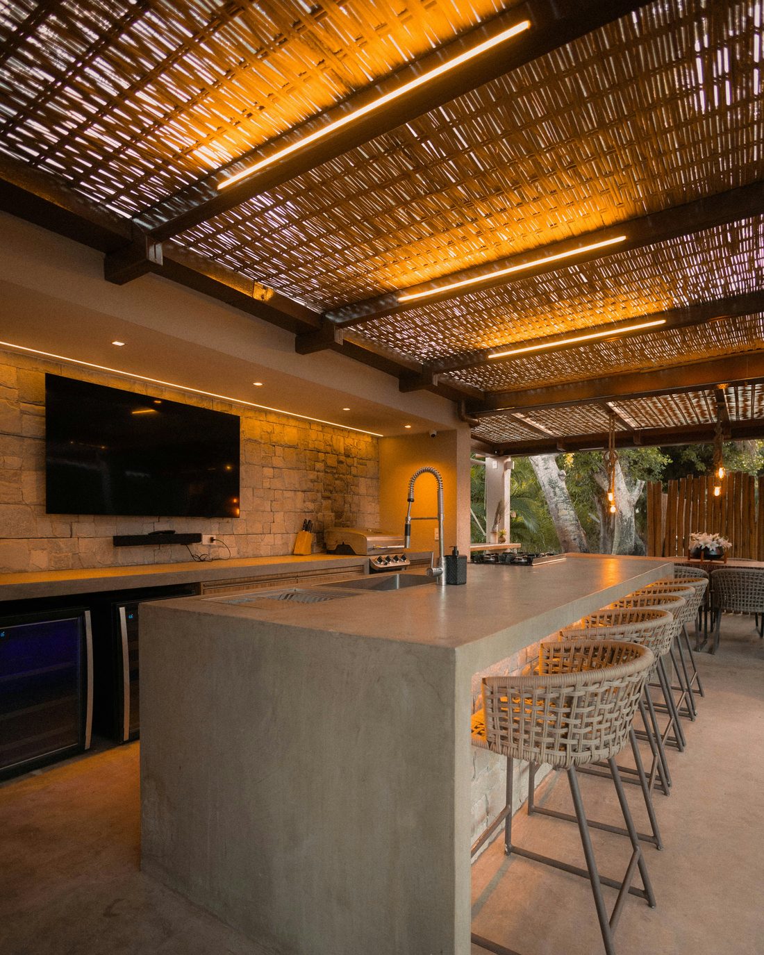 Covered outdoor kitchen with concrete bar under a slatted pergola